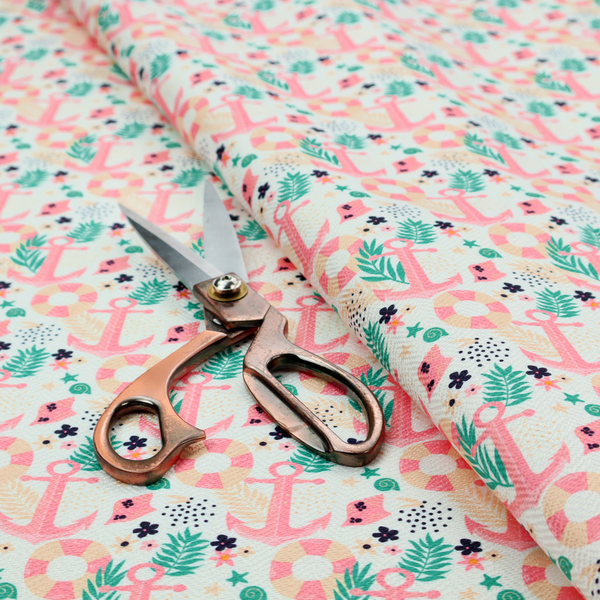 A light mint green fabric with a repeating nautical pattern featuring pink anchors framed by teal palm fronds, interspersed with pink and white striped life rings, tiny dark blue flowers, and small coral shells.