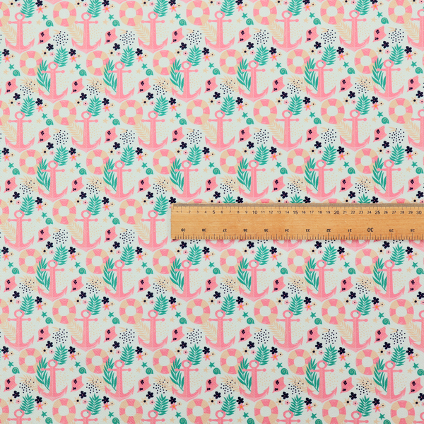 A light mint green fabric with a repeating nautical pattern featuring pink anchors framed by teal palm fronds, interspersed with pink and white striped life rings, tiny dark blue flowers, and small coral shells.