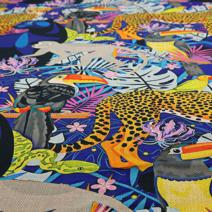 A vibrant jungle-themed fabric on a rich blue background featuring a repeating pattern of yellow leopards with black spots, blue panthers, toucans with bright orange and yellow beaks, light grey monkeys, small yellow-and-red birds, and lush tropical leaves and pink flowers.
