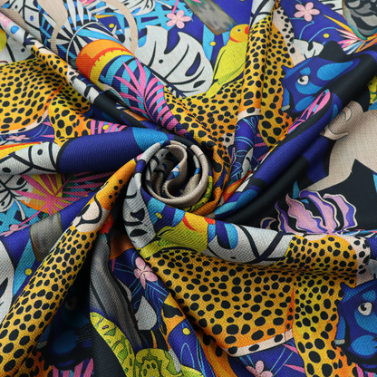 A vibrant jungle-themed fabric on a rich blue background featuring a repeating pattern of yellow leopards with black spots, blue panthers, toucans with bright orange and yellow beaks, light grey monkeys, small yellow-and-red birds, and lush tropical leaves and pink flowers.