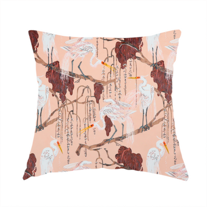 The fabric used to create this handmade cushion is a peach-pink fabric with an illustrated botanical and avian pattern featuring white egrets perched on brown branches among dark red, stylized foliage and weeping floral tendrils.