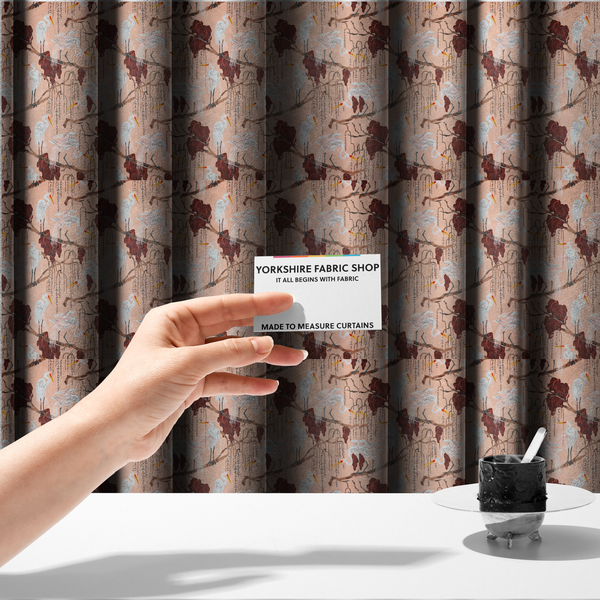 the fabric used to create these made-to-measure curtains is a peach-pink fabric with an illustrated botanical and avian pattern featuring white egrets perched on brown branches among dark red, stylized foliage and weeping floral tendrils.