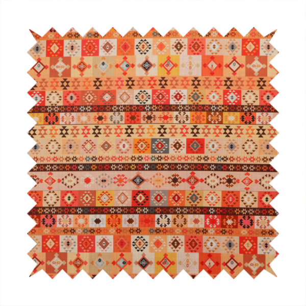 A geometric woven fabric featuring horizontal rows of Aztec and tribal-inspired patterns in warm earthy tones of orange, red, yellow, beige, brown, and dark charcoal.