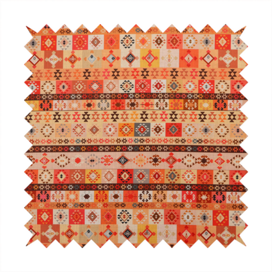 A geometric woven fabric featuring horizontal rows of Aztec and tribal-inspired patterns in warm earthy tones of orange, red, yellow, beige, brown, and dark charcoal.