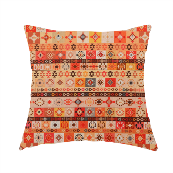 The fabric used to create this handmade cushion is a geometric woven fabric featuring horizontal rows of Aztec and tribal-inspired patterns in warm earthy tones of orange, red, yellow, beige, brown, and dark charcoal.