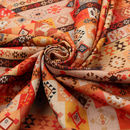 A geometric woven fabric featuring horizontal rows of Aztec and tribal-inspired patterns in warm earthy tones of orange, red, yellow, beige, brown, and dark charcoal.