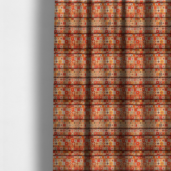 The fabric used to create these made-to-measure curtains is a geometric woven fabric featuring horizontal rows of Aztec and tribal-inspired patterns in warm earthy tones of orange, red, yellow, beige, brown, and dark charcoal.