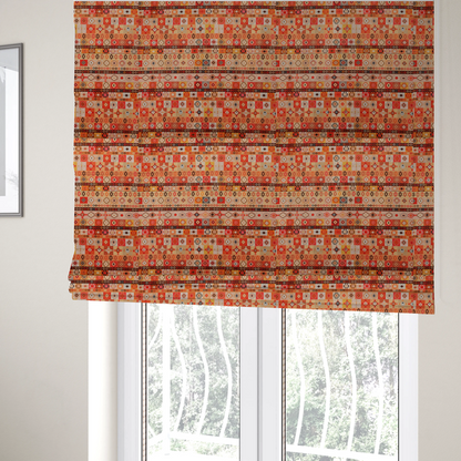 The fabric used to create these Roman blinds is a geometric woven fabric featuring horizontal rows of Aztec and tribal-inspired patterns in warm earthy tones of orange, red, yellow, beige, brown, and dark charcoal.