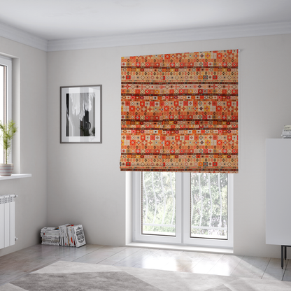 The fabric used to create these Roman blinds is a geometric woven fabric featuring horizontal rows of Aztec and tribal-inspired patterns in warm earthy tones of orange, red, yellow, beige, brown, and dark charcoal.