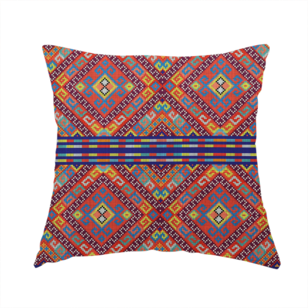 The fabric used to create this handmade cushion is a vibrant geometric fabric featuring a detailed pixelated pattern of large interlocking diamonds in red, blue, purple, yellow, and turquoise, separated by horizontal striped bands of multi-coloured dots on a dark blue background, reminiscent of traditional beadwork or woven textile art.