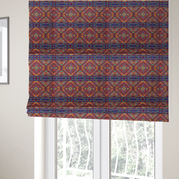 The fabric used to create these Roman blinds is a vibrant geometric fabric featuring a detailed pixelated pattern of large interlocking diamonds in red, blue, purple, yellow, and turquoise, separated by horizontal striped bands of multi-coloured dots on a dark blue background, reminiscent of traditional beadwork or woven textile art.