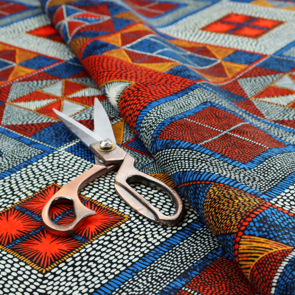 A geometric African wax print fabric featuring an intricate repeating pattern of nested diamonds, squares, and triangular motifs.