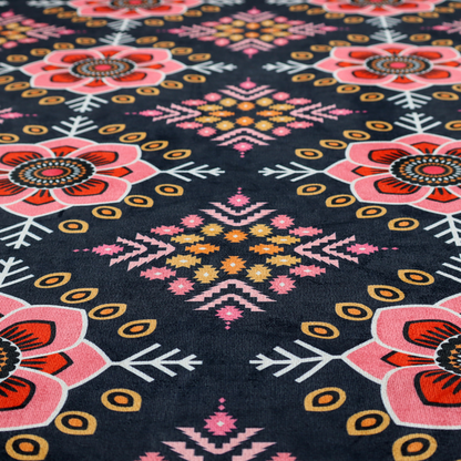 A repeating folk-art textile design featuring alternating rows of stylized pink floral blossoms and intricate diamond-shaped geometric motifs.