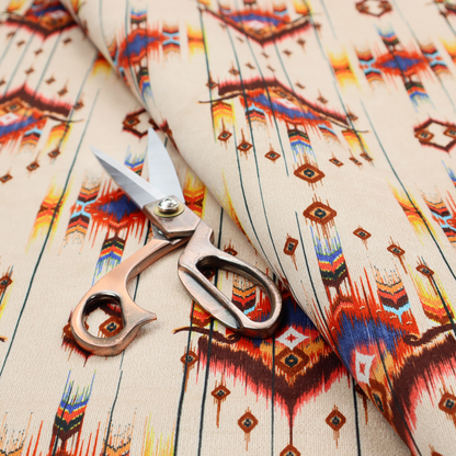 An off-white fabric featuring a vibrant Southwestern Aztec and ikat-style geometric pattern.