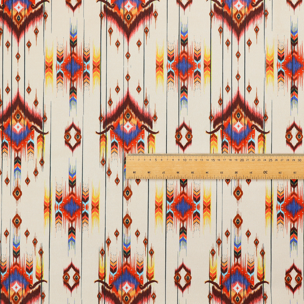 An off-white fabric featuring a vibrant Southwestern Aztec and ikat-style geometric pattern.