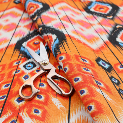 A vibrant orange fabric featuring a bold Southwestern Aztec and ikat-style geometric pattern.