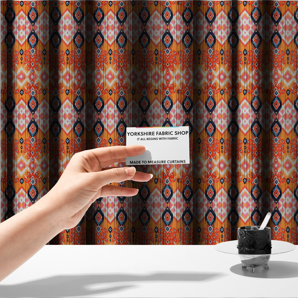 The fabric used to create these made-to-measure curtains is a vibrant orange fabric featuring a bold Southwestern Aztec and ikat-style geometric pattern.