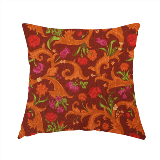 The fabric used to create this handmade cushion is a repeating pattern of ornate, golden-orange baroque scrolls and acanthus leaves intermixed with detailed botanical elements including red roses, magenta tulips, and green foliage, all set against a deep crimson red background.