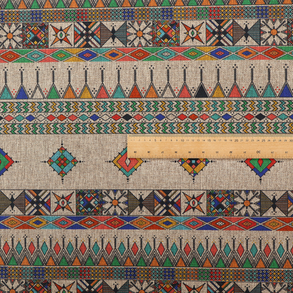 A multi-coloured ethnic geometric fabric with repeating rows of colourful tribal diamonds, zigzags, and striped borders set against a light neutral background.