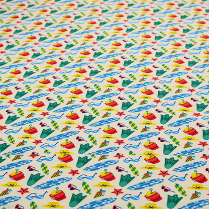 A vibrant, repeating beach-themed pattern on a light cream background, featuring small illustrations of blue and white surfboards, red buckets, green swim flippers, sunglasses, yellow sunhats, starfishes, and popsicles.