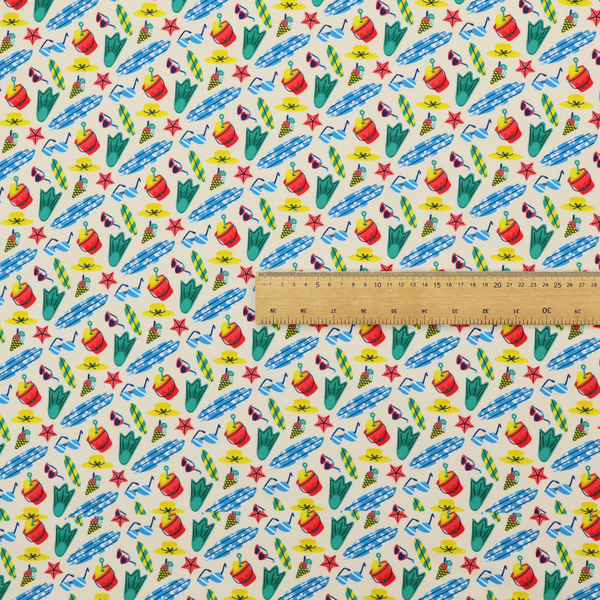 A vibrant, repeating beach-themed pattern on a light cream background, featuring small illustrations of blue and white surfboards, red buckets, green swim flippers, sunglasses, yellow sunhats, starfishes, and popsicles.