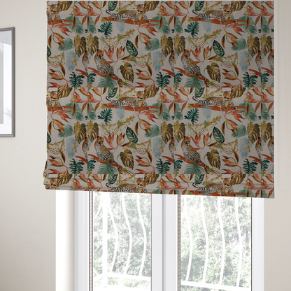 The fabric used to create these Roman blinds is a lounging leopards surrounded by vibrant tropical leaves, monstera fronds, and vines on a light-coloured background.