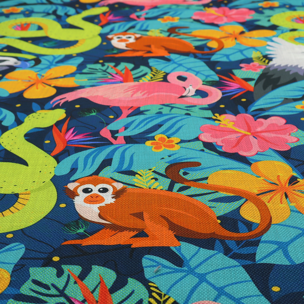 Vibrant jungle fabric pattern featuring neon green snakes, orange monkeys, pink flamingos, and harpy eagles surrounded by tropical flowers and blue foliage on a dark blue background.