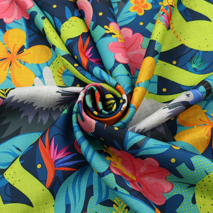 Vibrant jungle fabric pattern featuring neon green snakes, orange monkeys, pink flamingos, and harpy eagles surrounded by tropical flowers and blue foliage on a dark blue background.