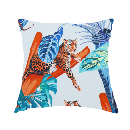 The fabric used to create this handmade cushion has leopards resting on orange branches amidst vibrant blue and turquoise tropical leaves and foliage against a light background.