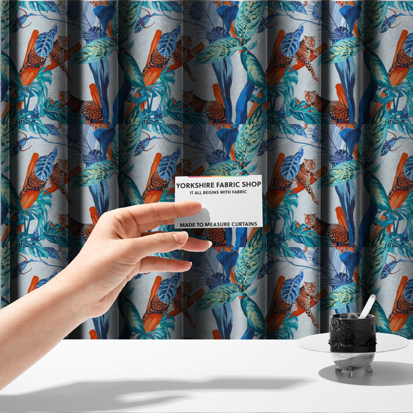 The fabric used to create these made-to-measure curtains has leopards resting on orange branches amidst vibrant blue and turquoise tropical leaves and foliage against a light background.