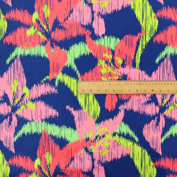 A vibrant fabric pattern featuring large coral and light pink lily flowers with bright lime green leaves against a solid royal blue background.