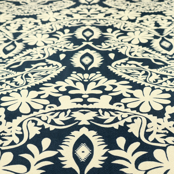 A dark midnight blue fabric featuring an ornate, repeating damask pattern in creamy off-white, composed of intricate scrollwork, floral motifs, and symmetrical ogee shapes.