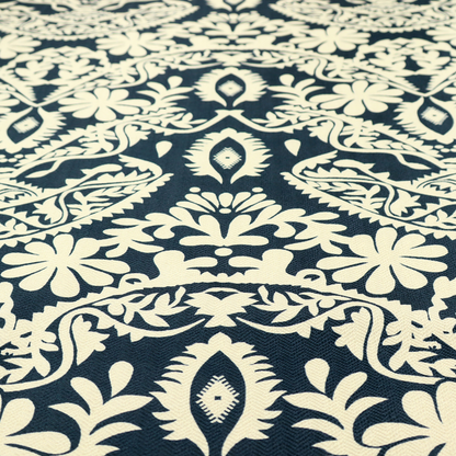 A dark midnight blue fabric featuring an ornate, repeating damask pattern in creamy off-white, composed of intricate scrollwork, floral motifs, and symmetrical ogee shapes.