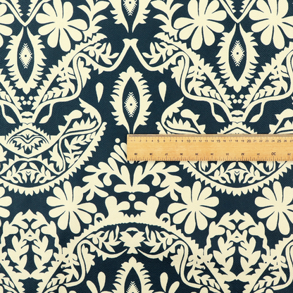 A dark midnight blue fabric featuring an ornate, repeating damask pattern in creamy off-white, composed of intricate scrollwork, floral motifs, and symmetrical ogee shapes.