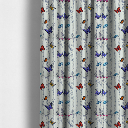 The fabric used to create these made-to-measure curtains is a light-coloured fabric featuring a pattern of vertical grey and white birch tree trunks interspersed with colourful butterflies in shades of red, orange, yellow, blue, and purple.