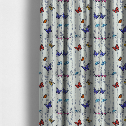 The fabric used to create these made-to-measure curtains is a light-coloured fabric featuring a pattern of vertical grey and white birch tree trunks interspersed with colourful butterflies in shades of red, orange, yellow, blue, and purple.