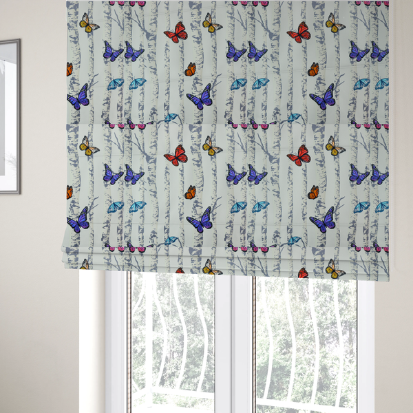 The fabric used to create these Roman blinds is a light-coloured fabric featuring a pattern of vertical grey and white birch tree trunks interspersed with colourful butterflies in shades of red, orange, yellow, blue, and purple.