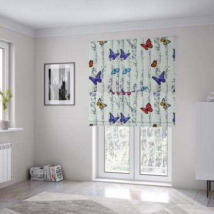 The fabric used to create these Roman blinds is a light-coloured fabric featuring a pattern of vertical grey and white birch tree trunks interspersed with colourful butterflies in shades of red, orange, yellow, blue, and purple.