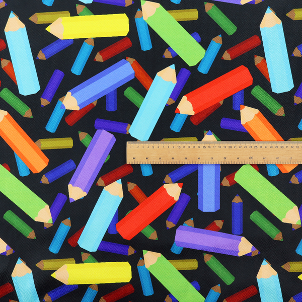 A black fabric featuring a playful, repeating pattern of coloured pencils in various shades including red, yellow, light blue, green, purple, and orange scattered diagonally across the background.