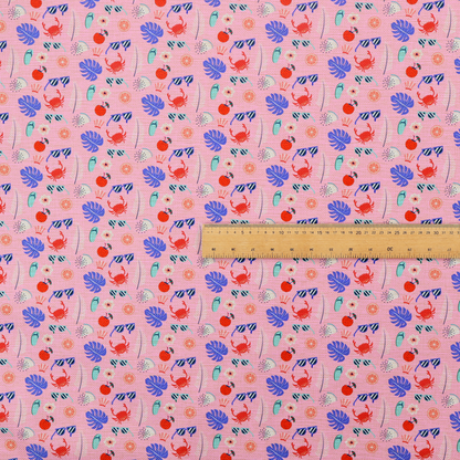 Pink summer-themed fabric featuring a repeating pattern of tropical icons including crabs, sunglasses, cherries, flip-flops, palm leaves, citrus slices, and flowers.