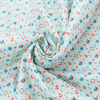 Light blue fabric featuring a small-scale repeating nautical pattern of red anchors, lifebuoys, and sailboats, interspersed with blue and red stars.