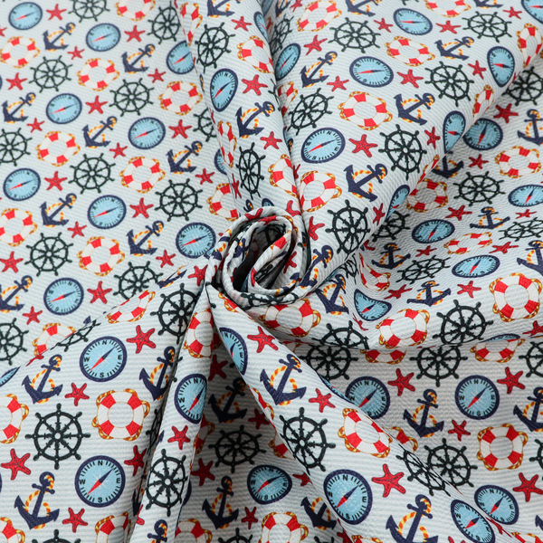 Light blue fabric with a dense repeating nautical pattern featuring dark blue anchors, black ship wheels, blue compasses, red-and-white lifebuoys, and tiny red stars.