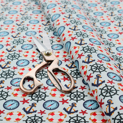 Light blue fabric with a dense repeating nautical pattern featuring dark blue anchors, black ship wheels, blue compasses, red-and-white lifebuoys, and tiny red stars.