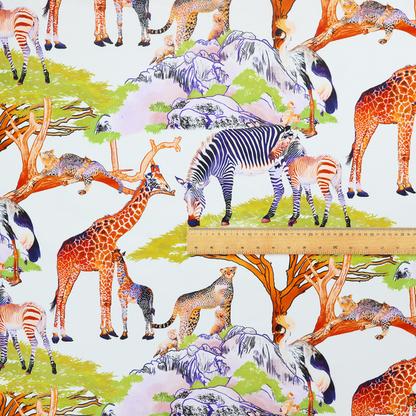 Fabric pattern featuring a vibrant African savanna landscape with giraffes, zebras, cheetahs, and birds among acacia trees and rocky terrain.