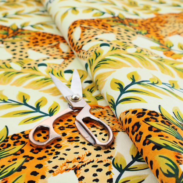 Fabric pattern featuring a symmetrical design of spotted leopards surrounded by golden and green tropical foliage and palm leaves.