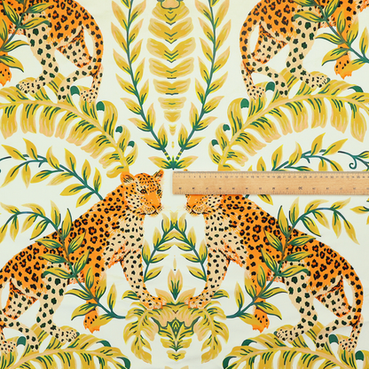 Fabric pattern featuring a symmetrical design of spotted leopards surrounded by golden and green tropical foliage and palm leaves.