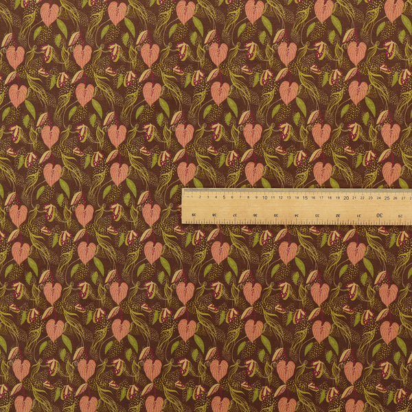 A brown upholstery fabric featuring a repeating pattern of pink heart-shaped leaves, green foliage, and delicate botanical details.