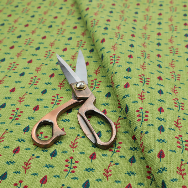 A green upholstery fabric featuring a ditsy folk-art pattern of small red berries, sprigs, and dark blue leaves.