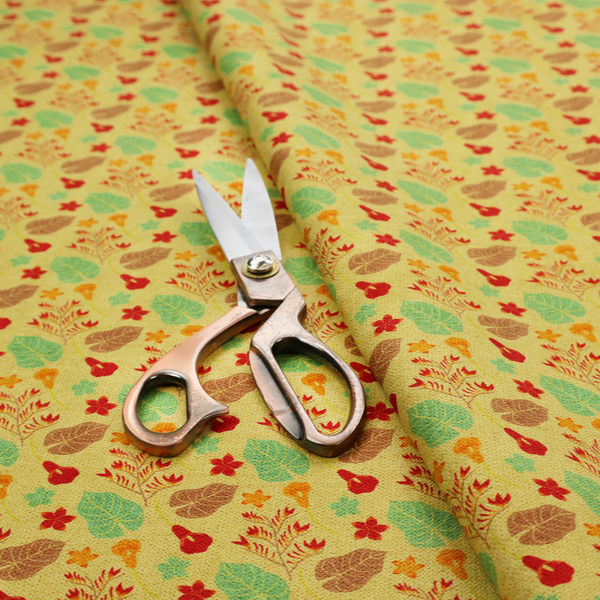 A yellow upholstery fabric featuring a vibrant tropical pattern of red, green, and brown leaves and flowers.