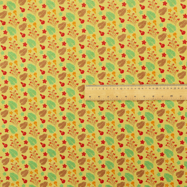 A yellow upholstery fabric featuring a vibrant tropical pattern of red, green, and brown leaves and flowers.